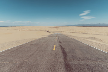 a road in the middle of the sand dunes in the desert.
