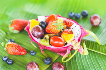 Fruit salad bowl served in a dragon fruit and vegetables healthy organic food strawberries orange kiwi blueberries grape pineapple tomato lemon fresh summer fruits tropical on banana leaf