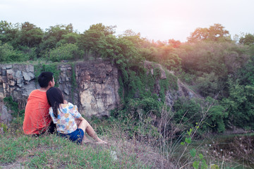 Asian romantic couple in love sitting on grass field and cliff of the mountain.