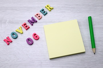 November 6 - Daily colorful Calendar with Block Notes and Pencil on wood table background, empty space for your text or design