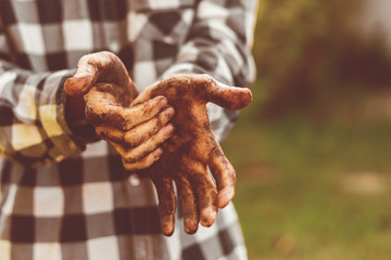 dirty working farmer hands in soil standing in garden