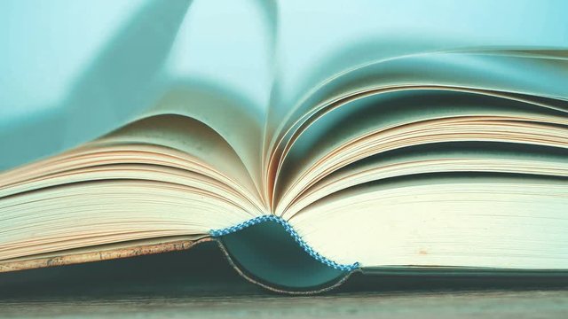 close up opened book on the table , wind turning the book page ,reading textbook or  learning education concept