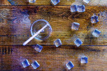 Glass of soda water and scattered melting ice cubes around.Above view