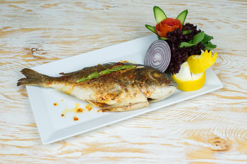 Grilled or fried fish on a plate with vegetables