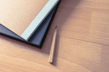 Blank notebook with textbook and pencil on wooden floor. Minimal and simple style.