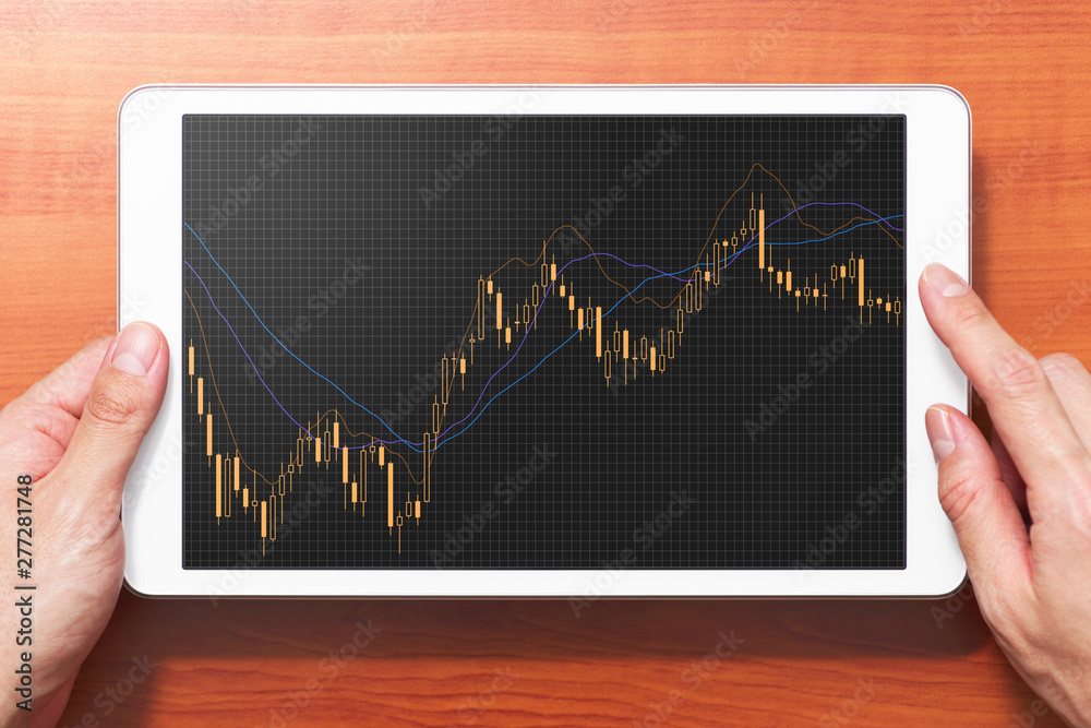 Poster stock market candlestick chart on tablet computer screen. tablet computer on wooden desk.