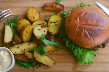 Meat burger with fries, mayonnaise potatoes on a wooden board. Restaurant dish. Food in the cafe, eatery. Fast food. A fat dish. burger with meat and lettuce. Board on the tablecloth in the cell