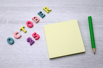 October 25 - Daily colorful Calendar with Block Notes and Pencil on wood table background, empty space for your text or design