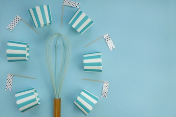Baking concept. Blue muffin molds, a whisk on a light blue background
