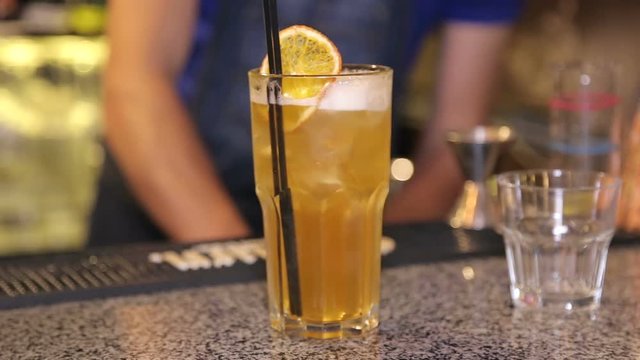 Fresh cocktail with orange, limet, mint and ice at the bar counter. Fresh citrus cocktail with ice and black cocktail tube on the bar.