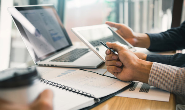 Business partnership coworkers using a tablet to chart company financial statements report and profits work progress and planning in office room.