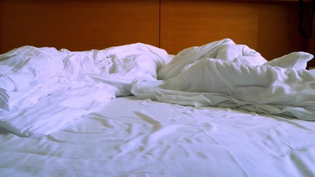 Panning shot of messy hotel bed after great night. Romance and love feeling.