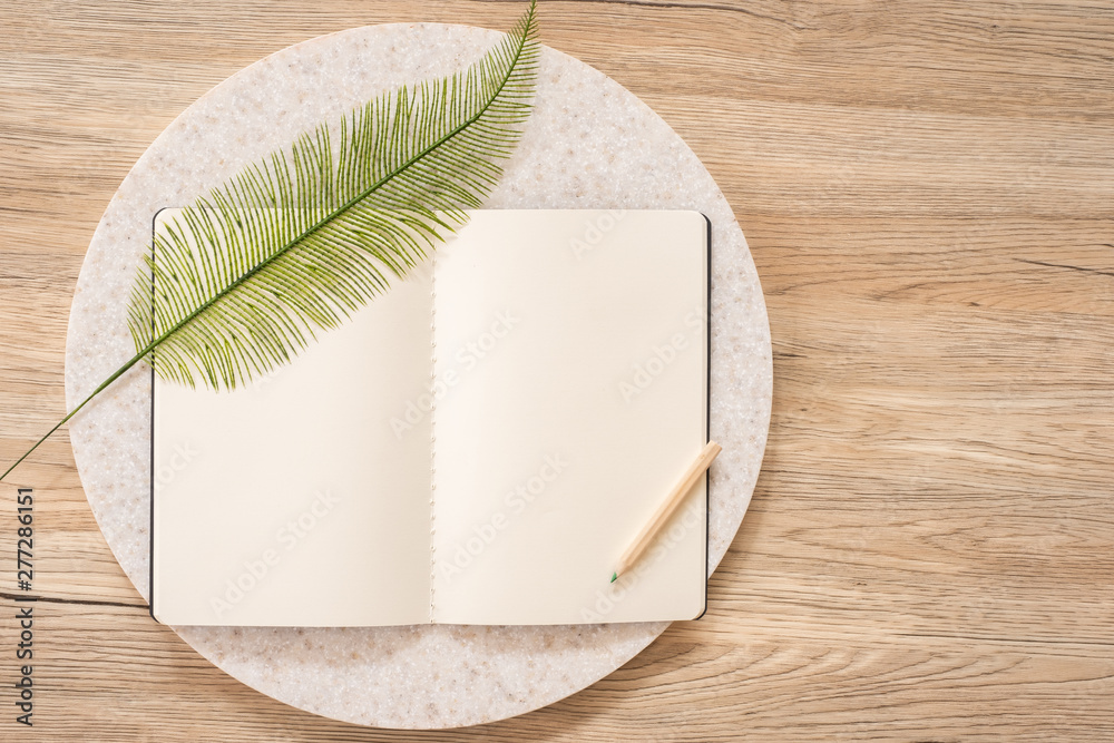 Aufkleber top view of open notebook with leaf and pencil on wooden table with copy space.eco sustainable concept.