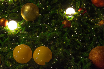 Obraz na płótnie Canvas Illuminated decoration of Christmas tree with hanging golden yellow and red ball.