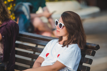 woman in white t-shirt and white sunglasses sitting on city bench