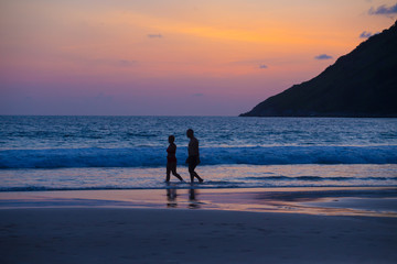 couple are enjoying beautiful sunset walking on the beach at Nai Harn beach in Phuket island, Thailand 2019 july