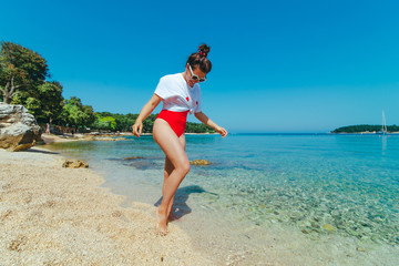 sexy woman in red swimsuit and white t-shirt at sea beach