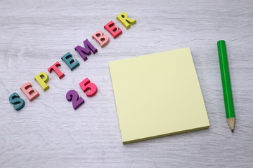 September 25 - Daily colorful Calendar with Block Notes and Pencil on wood table background, empty space for your text or design