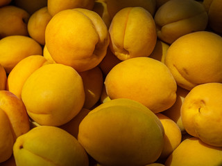 Ripe, sweet apricots in a wooden box on the market. The sun lights the apricots on the market