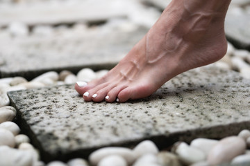 A female leg is standing on the stone floor of a large open-air bathroom. Interior Buddhist
