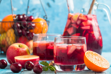 Refreshing sangria or punch with fruits in glasses and pincher