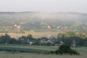 Early summer morning in the Ukrainian village. Dal covered with blue morning fog.