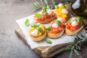 Bruschetta with tomato, basil and mozzarella cheese on wooden board. Traditional italian appetizer or snack, antipasto
