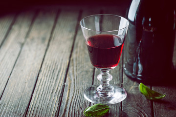 Red Wine glass and a bottle on dark wooden background