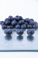 A mountain of big blueberries and three on a glass plate - Big and sweet blueberries