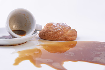 Puff pastry roll with powdered sugar on top and spilled coffee