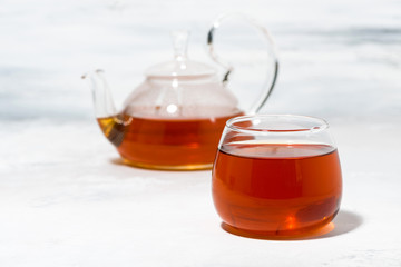 glass cup of tea and teapot on white table