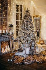 warm cozy evening in Christmas room interior design,Xmas tree decorated by lights gifts,toys, deer,candles, lanterns, garland lighting indoors fireplace.holiday.magic New year