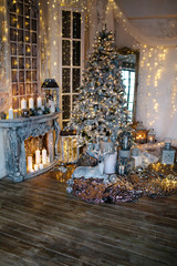 warm cozy evening in Christmas room interior design,Xmas tree decorated by lights gifts,toys, deer,candles, lanterns, garland lighting indoors fireplace.holiday.magic New year