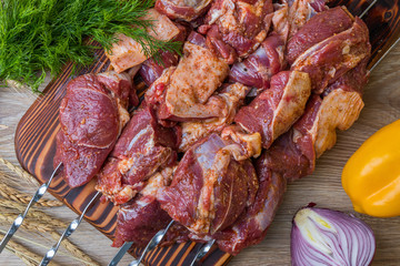Raw meat on skewers in marinade with vegetables and spices. Top view.