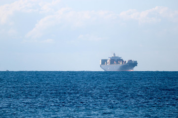 Distant view in haze of a large cargo container ship in the Mediterranean sea near Livorno, Italy