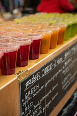 Obraz premium close up of plastic cups in a row filled with fresh juice at Stockbridge weekly market.