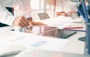 Closeup shot of businessman hand using stylus pen on digital tablet at office desk.