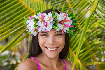 Tahiti flower crown hei po'o smiling woman wearing tahitian headpiece wreath cultural decoration. Bora Bora, French Polynesia. Beauty Asian multiracial model smile on palm tree background. - obrazy, fototapety, plakaty