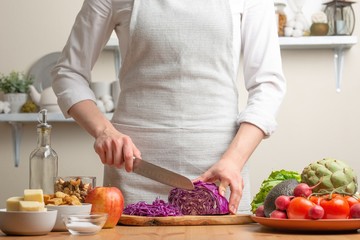 The cook cuts purple cabbage for salad, the concept of tasty and healthy food, diet, vegetarian food, detox