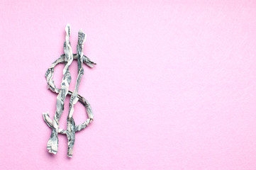 Twisted one hundred dollar banknotes in a USD sign shape on pink background. American dollar's icon/sign.