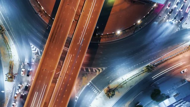 Hyperlapse timelapse of night city traffic on 4-way stop street intersection circle roundabout in bangkok, thailand. 4K UHD horizontal aerial view.