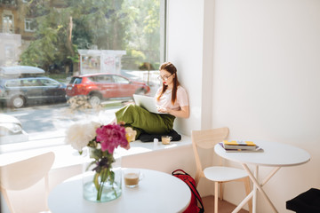 Relaxed longhaired girl leaning on wall during work