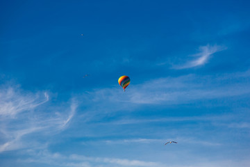 Balloon flying through the blue sky among the clouds. Freedom, adventure, loneliness. Birds are stolen around