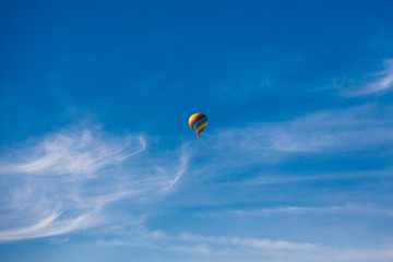 Balloon flying through the blue sky among the clouds. Freedom, adventure, loneliness.