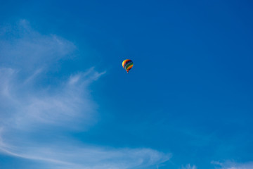 Balloon flying through the blue sky among the clouds. Freedom, adventure, loneliness.