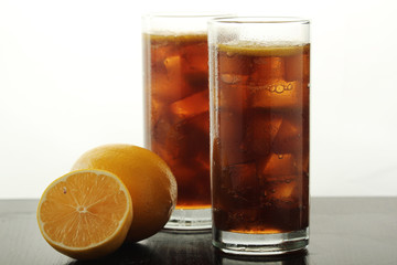 Glasses with cuba libre cocktail or cola with ice or cold tea with lemon