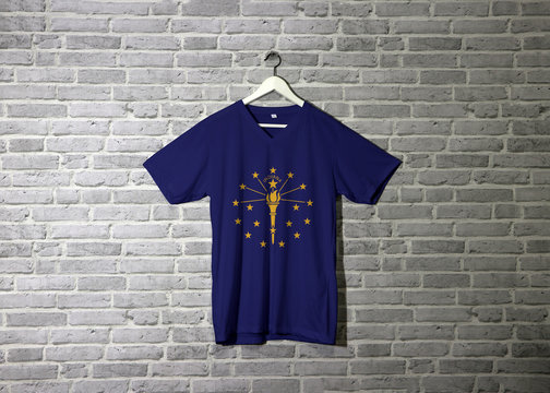 Indiana flag on shirt and hanging on the wall with brick pattern wallpaper.