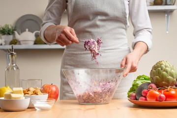 The chef mixes the salad, stir, in the process of a vegetarian salad in the home kitchen. Light background for restaurant menu design, menu, recipe book. Healthy food, detox