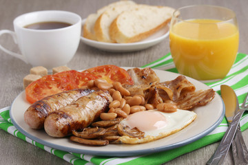 Classic English breakfast served: eggs, bacon, beans, juice and tea	