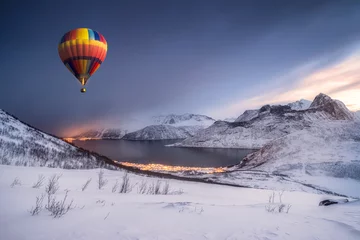 Foto op Plexiglas Ballon Hot air balloon flying on snow hill with fordgard town in winter